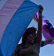 A imagem mostra uma pessoa negra segurando uma bandeira da população trans. Relatório revela que pessoas afetadas pelo racismo são maioria nos registros de assassinatos.  Foto: Alma Preta