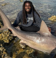 Um homem, apelidado de "Aquaman da vida real", ganhou destaque nas redes sociais depois de ser visto segurando um tubarão com as mãos   Foto: Foto: reprodução @hoodfishing_entertainment