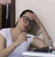 Mulher mede a febre com um termômetro  Foto: iStock