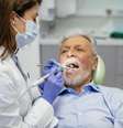 Homem idoso é avaliado por dentista  Foto: iStock