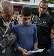 Dois homens e dois meninos em uma rua em Gaza olham para um folheto com alerta de evacuação emitido pelas FDI  Foto: Getty Images / Anadolu / BBC News Brasil