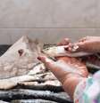 Mulher limpando escamas de peixe de uma sardinha à mão na cozinha de casa  Foto: David Petrus Ibars/iStock