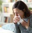 Mulher adulta doente tossindo cobrindo boca com tecido em casa  Foto: Pheelings Media/iStock