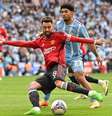  Foto: Glyn Kirk / AFP via Getty Images - Legenda: Bruno Fernandes chuta para fazer o terceiro gol do United contra o Coventry, pela Copa da Inglaterra / Jogada10