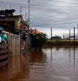 Homem escala portão de casa em Eldorado, Rio Grande do Sul, em meio à enchente  Foto: REUTERS/Amanda Perobelli