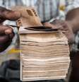 Homem manipula grande maço de notas de naira  Foto: Getty Images / BBC News Brasil