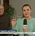 Isabela Sabéllico segurando a medalha de Santo Antônio, ao lado do frei Gilberto Piscitelli, responsável pelo 'bolo do desencalhe'  Foto: Reprodução/TV