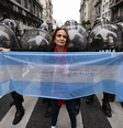 Manifestante segura bandeira argentina na frente de policiais nos arredores do Congresso Nacional em Buenos Aires.  Foto:  Luis Robayo/AFP