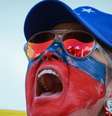 Manifestante com o rosto pintado de vermelho e azul, usando óculos e boné também nas cores azul e vermelho  Foto: Getty Images / BBC News Brasil