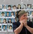 Mulher chorando ao ver as fotos das vítimas do ataque no ginásio da escola de Beslan.  Foto: Getty Images / BBC News Brasil