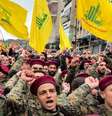 Integrantes do Hezbollah em uniformes militares marcham com bandeiras do grupo ao fundo.  Foto: Getty Images / BBC News Brasil