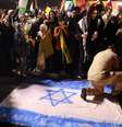 Iraniano pisa em bandeira de Israel durante comemoração em Teerã pelos ataques com mísseis nesta terça-feira (01/10)  Foto: Majid Asgaripour/WANA via REUTERS / BBC News Brasil