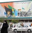 Mulher passa em frente a pintura do líder supremo do Irã aiatolá Ali Khamenei e o antecessor Ruhollah Khomeini em Teerã  Foto: EPA / BBC News Brasil