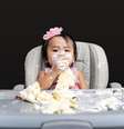 Menina na cadeirinha comendo bolo, que está espalhado pela mesa  Foto: Getty Images / BBC News Brasil