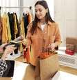 Mulher pagando a conta das suas compras de roupas.  Foto: Freepik