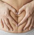 Mulher com as mãos em volta da barriga.  Foto: Freepik