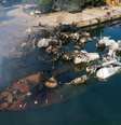 Um grande barco afundado perto do cais na cidade portuária síria de Latakia. Há fumaça subindo e estruturas metálicas parcialmente submersas.  Foto: Getty Images / BBC News Brasil