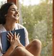 Mulher feliz com seu livro nas mãos.  Foto: Freepik