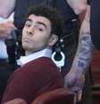 Luigi Mangione sentado ao lado de policiais durante depoimento no tribunal  Foto: Getty Images / BBC News Brasil