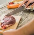 Homem usando tábua de corte para preparar carne vermelha.  Foto: Freepik