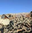 Pessoas em cima de uma casa desabada, ao lado de uma pilha de escombros. Ao fundo, montanhas.  Foto: Reuters / BBC News Brasil