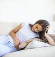 Mulher deitada no sofá com inchaço abdominal   Foto: Freepik