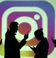 Pessoas utilizando o celular diante da logo do Instagram  Foto: Dado Ruvic / Reuters