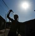 Um homem se refresca com uma mangueira na rua durante uma onda de calor em Guaratiba, no subúrbio do Rio de Janeiro, Brasil, 17 de fevereiro de 2025  Foto: REUTERS/Tita Barros