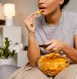 Mulher comendo salgadinhos  Foto: Freepik