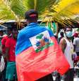 Um migrante haitiano com a bandeira nacional do Haiti, enquanto milhares de migrantes haitianos, africanos e cubanos tentam atravessar para a fronteira entre a Colômbia e o Panamá de barco, com o objetivo de seguir rumo aos Estados Unidos.  Foto: Getty Images / BBC News Brasil