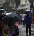 Pedestres se protegem da chuva, com termômetros marcando 23ºC graus, na região central da capital paulista, na tarde desta sexta-feira, 04 de abril de 2025.  Foto: CRIS FAGA/DRAGONFLY PRESS/ESTADÃO CONTEÚDO