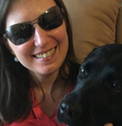 Danieli Haloten sentada com a labradora preta Elva, sua cão-guia aposentada, em seu colo em uma foto publicada no Instagram  Foto: Reprodução/Instagram / Contigo