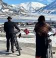 Noruegueses andando de bicicleta em Svalbard, com picos cobertos de neve ao fundo  Foto: BBC News Brasil