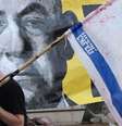 Um homem com uma bandeira israelense passa por um cartaz com a foto de Netanyahu  Foto: JACK GUEZ/AFP via Getty Images / BBC News Brasil