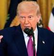 Donald Trump de terno com a mão levantada, em frente a bandeiras dos EUA  Foto: Getty Images / BBC News Brasil