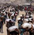 Palestinos caminham com sacos de farinha depois que caminhões carregados de ajuda humanitária entraram no norte de Gaza, em 27 de julho de 2025.  Foto: © BASHAR TALEB / AFP / RFI