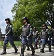 Policiais em equipamento anti-motim marcham em frente ao Domo da Bomba Atômica (ao fundo, à esquerda) enquanto protegem a área um dia antes das cerimônias que marcam o 80º aniversário do primeiro bombardeio atômico do mundo, na cidade de Hiroshima, província de Hiroshima, em 5 de agosto de 2025.  Foto: AFP - RICHARD A. BROOKS / RFI