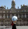 Uma mulher usa uma sombrinha para se proteger do calor em Lyon, no sudeste da França, onde são previstos até 42°C nesta quarta-feira, 13 de agosto de 2025.  Foto: REUTERS - Abdul Saboor / RFI