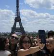 Turistas posam para uma selfie com a Torre Eiffel ao fundo em 6 de julho de 2023, em Paris (imagem ilustrativa).  Foto: AP - Michel Euler / RFI