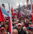 Manifestantes seguram bandeiras nacionais da Polônia durante um protesto antimigração convocado pelo partido nacionalista Lei e Justiça, na Praça do Castelo Real, em Varsóvia, em 11 de outubro de 2025.  Foto: AFP - WOJTEK RADWANSKI / RFI
