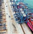Vista aérea de um navio em um porto de contêineres com muitos contêineres no navio e também no lado do porto esperando para serem carregados  Foto: Getty Images / BBC News Brasil