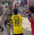 Um menino que não aparenta ter mais que 12 anos se coloca entre a mulher e o policial militar  Foto: Reprodução/X