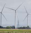 Turbinas eólicas terrestres no Parque Eólico Little Cheyne Court operam ao lado de torres de eletricidade em Dungeness, Grã-Bretanha, em 10 de julho de 2024. Ilustração.  Foto: © Chris J Ratcliffe / REUTERS / RFI