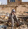Um sobrevivente do terremoto no Afeganistão senta sobre os escombros de uma casa destruída em uma vila de Tashqurghan, no distrito de Khulm, província de Samangan  Foto: AFP - ATIF ARYAN / RFI