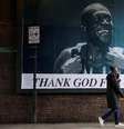 Uma pessoa passa por um outdoor com a imagem do rapper Stormzy, parte da campanha "Thank God For Immigrants" (Agradeça a Deus pelos Imigrantes) do grupo ativista Everyone Hates Elon, que celebra ícones imigrantes da cultura britânica, em Londres, Reino Unido, em 30 de outubro de 2025.  Foto: REUTERS - Hiba Kola / RFI