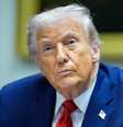 O presidente dos EUA, Donald Trump, sentado, com um terno azul, camisa azul, gravata vermelha e um broche na lapela com a bandeira do país  Foto: EPA/Shutterstock / BBC News Brasil