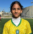 Uma menina palestina olha para a câmera. Ela está em um campo de futebol e veste a camisa da seleção brasileira  Foto: BBC News Brasil