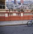 Moradores circulam de bicicleta nas ruas de Havana, em frente a um cartaz com imagens do presidente de Cuba, Miguel Díaz-Canel (à dir.), e de seus antecessores no cargo, Fidel (à esq.) e Raúl Castro, em 16 de fevereiro de 2026.  Foto: © Yamil Lage / AFP / RFI