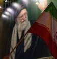 Uma bandeira nacional iraniana é hasteada em frente a uma faixa com a imagem de Ali Khamenei durante uma vigília em memória do líder supremo do Irã, Ali Khamenei, após a mídia estatal iraniana confirmar sua morte em 1º de março de 2026, em Teerã, Irã.  Foto: Majid Saeedi/Getty Images