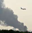 Avião da companhia aérea Emirates voa perto de colunas de fumaça de um incêndio perto do Aeroporto Internacional de Dubai, nos Emirados Árabes Unidos, no dia 16 de março de 2026  Foto: AFP via Getty Images / BBC News Brasil